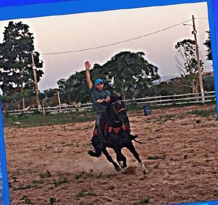 Kell montado a cavalo em uma arena de terra, acenando