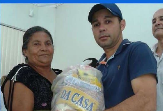Kell entregando uma cesta básica a uma moradora