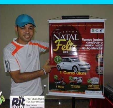 Kell apontando para o banner da campanha Natal Feliz do comércio de Açailândia